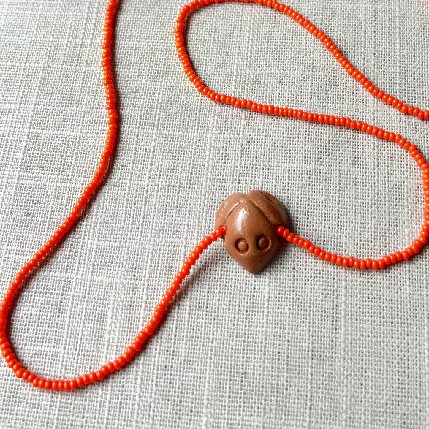 Collier en perles de verre (Miçanga) - orange et pendentif Muiraquitã - Ethnie Borari