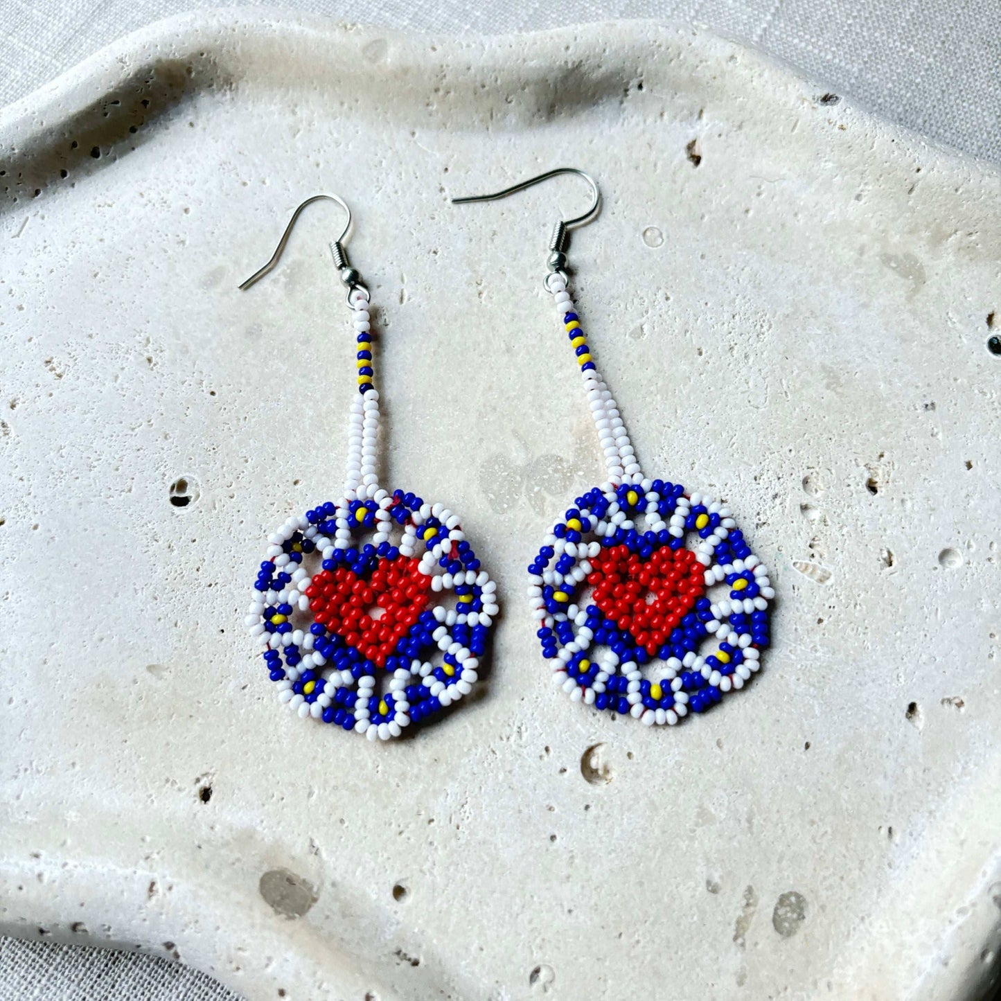 Boucles d'oreilles en perles de verre (miçanga) - Fleur bleu blanc coeur rouge - Ethnie Wai Wai Boucles d'oreilles Ethnie Wai Wai localisée dans les états de l' Amazonas, Pará et Roraima dans le Nord du Brésil.