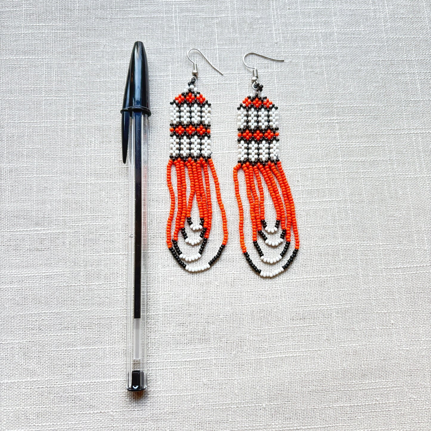 Boucles d'oreilles en perles de verre (miçanga) - orange et blanc - Ethnie Kayapo Boucles d'oreilles Ethnie Kayapo, localisée dans l'état du Pará au nord du Brésil