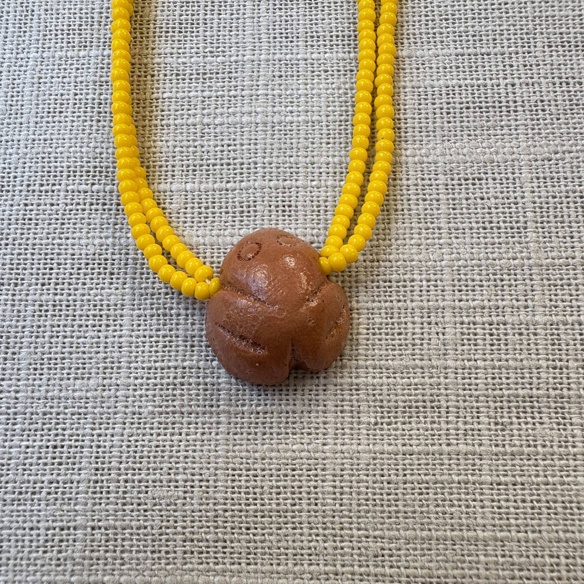 Colar em contas de vidro (Miçanga) - amarelo e pingente Muiraquitã