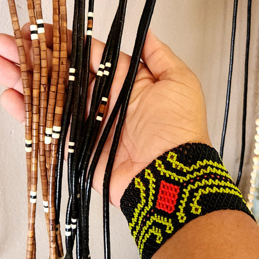 Pour le texte alternatif, je te conseille une Main tenant plusieurs bijoux artisanaux réalisés à partir de noyaux naturels.