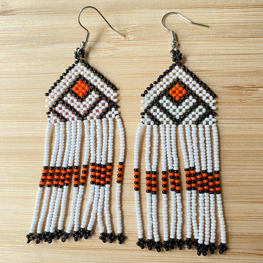 Boucles d'oreilles en perles de verre (miçanga) - Blanc noir et orange - Ethnie Wai Wai Boucles d'oreilles Ethnie Wai Wai localisée dans les états de l' Amazonas, Pará et Roraima dans le Nord du Brésil. 