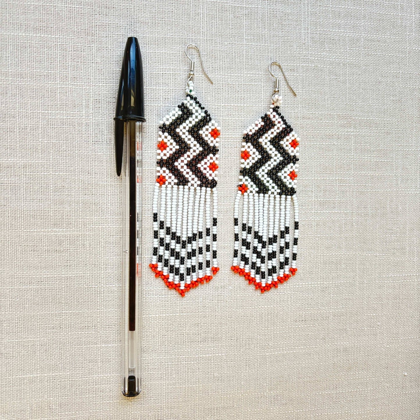 Boucles d'oreilles en perles de verre (miçanga) - blanc noir et pointes oranges - Ethnie Wai Wai Boucles d'oreilles Ethnie Wai Wai localisée dans les états de l' Amazonas, Pará et Roraima dans le Nord du Brésil. 