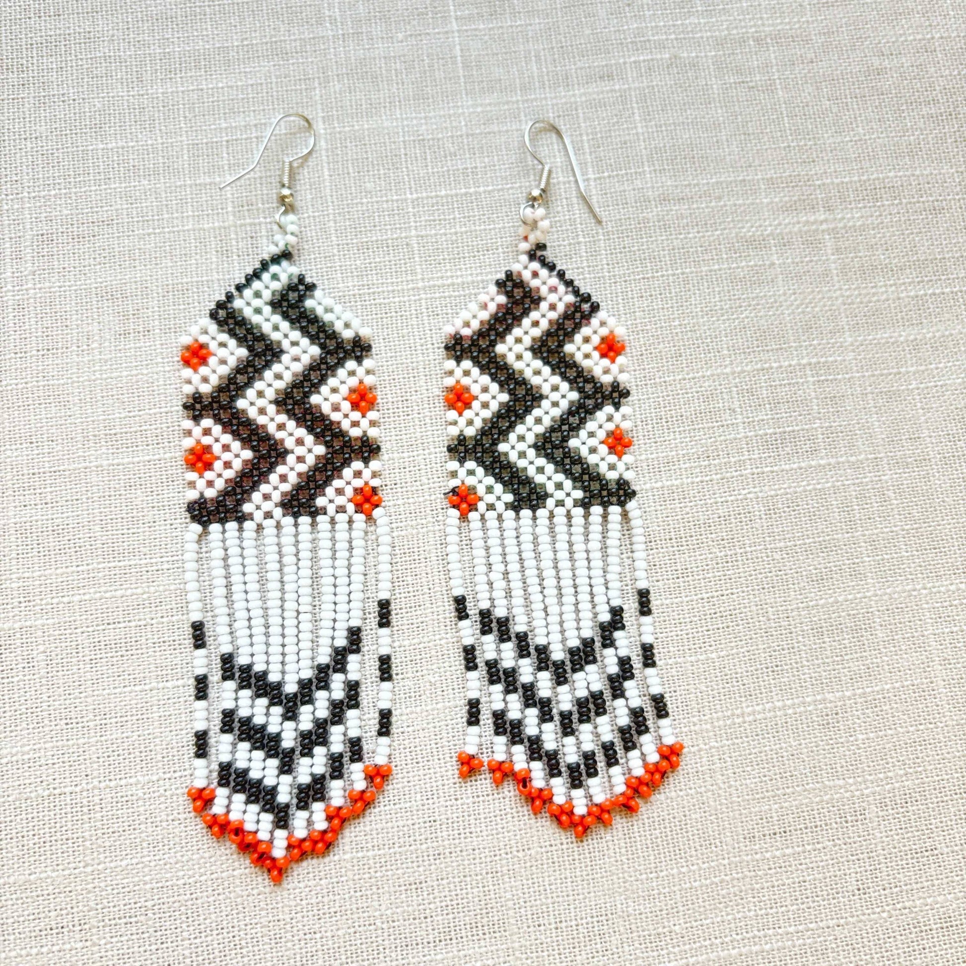 Boucles d'oreilles en perles de verre (miçanga) - blanc noir et pointes oranges - Ethnie Wai Wai Boucles d'oreilles Ethnie Wai Wai localisée dans les états de l' Amazonas, Pará et Roraima dans le Nord du Brésil. 