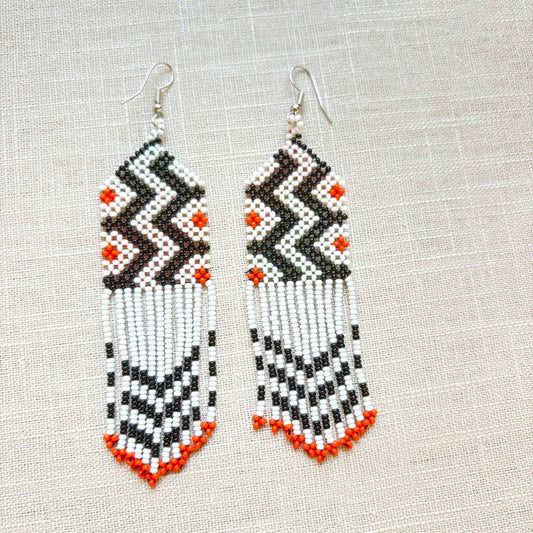 Boucles d'oreilles en perles de verre (miçanga) - blanc noir et pointes oranges - Ethnie Wai Wai Boucles d'oreilles Ethnie Wai Wai localisée dans les états de l' Amazonas, Pará et Roraima dans le Nord du Brésil. 