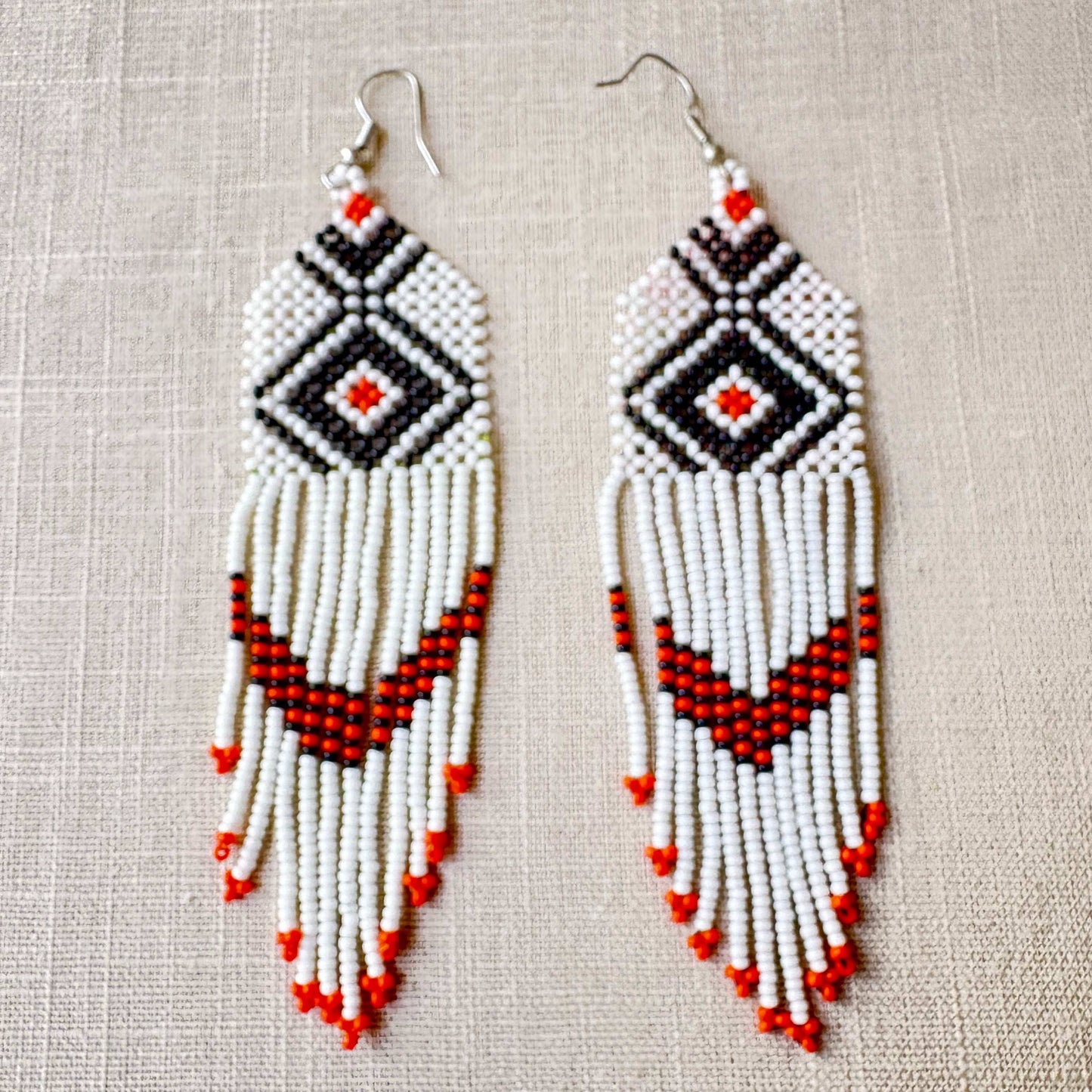 Boucles d'oreilles en perles de verre (miçanga) - blanches losange noir et orange - Ethnie Wai Wai Boucles d'oreilles Ethnie Wai Wai localisée dans les états de l' Amazonas, Pará et Roraima dans le Nord du Brésil. 