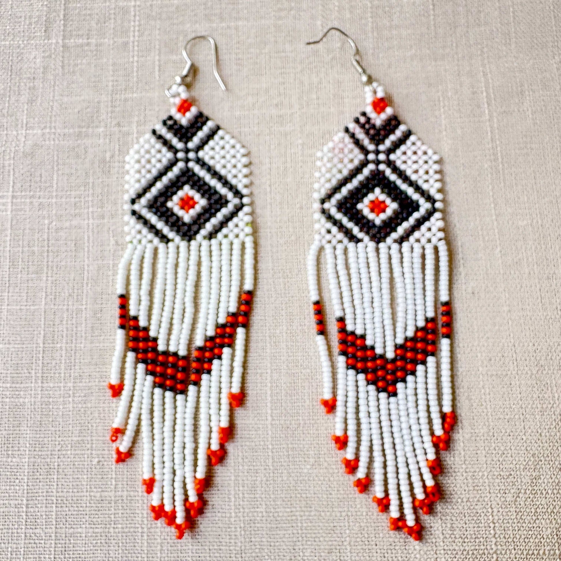 Boucles d'oreilles en perles de verre (miçanga) - blanches losange noir et orange - Ethnie Wai Wai Boucles d'oreilles Ethnie Wai Wai localisée dans les états de l' Amazonas, Pará et Roraima dans le Nord du Brésil. 