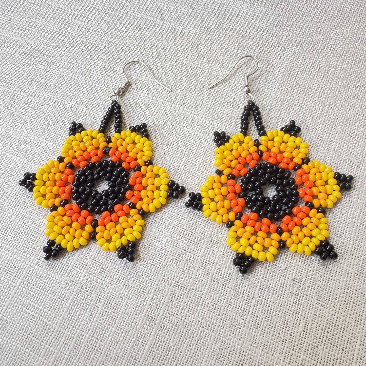 Boucles d'oreilles en perles de verre (miçanga) - Fleur noir jaune et orange - Ethnie Wai Wai Boucles d'oreilles Ethnie Wai Wai localisée dans les états de l' Amazonas, Pará et Roraima dans le Nord du Brésil. 