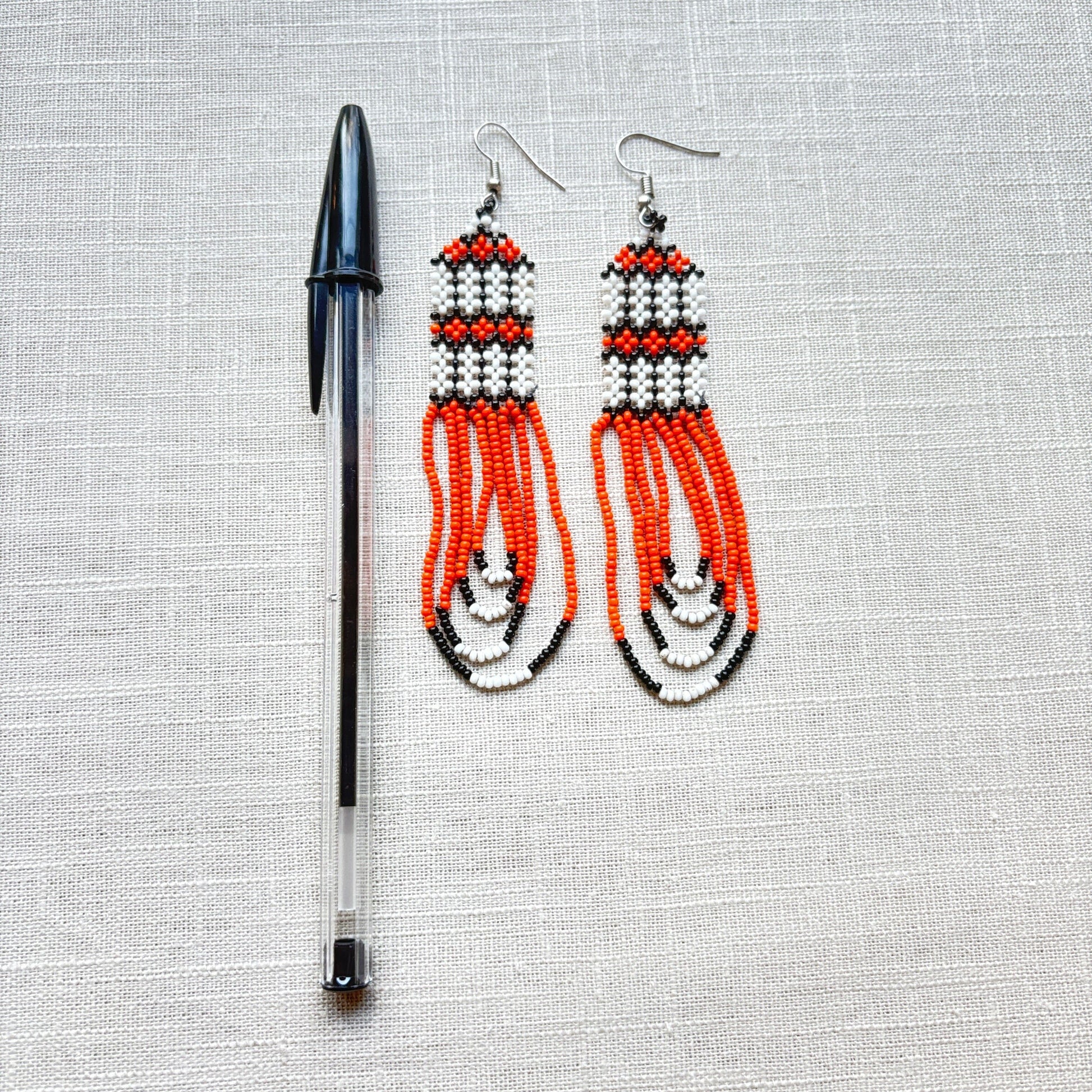 Boucles d'oreilles en perles de verre (miçanga) - orange et blanc - Ethnie Kayapo Boucles d'oreilles Ethnie Kayapo, localisée dans l'état du Pará au nord du Brésil 