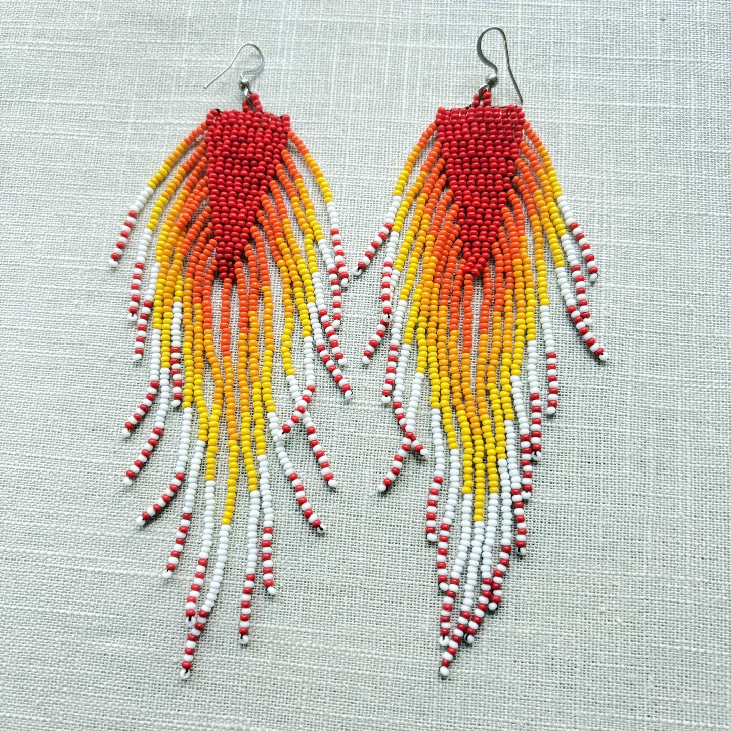 Boucles d'oreilles en perles de verre (Miçanga) - Rouge à franges orange blanc et jaune - Ethnie Borari Boucles d'oreilles Ethnie Borari, localisée dans l'état du Pará dans le Nord du Brésil. 