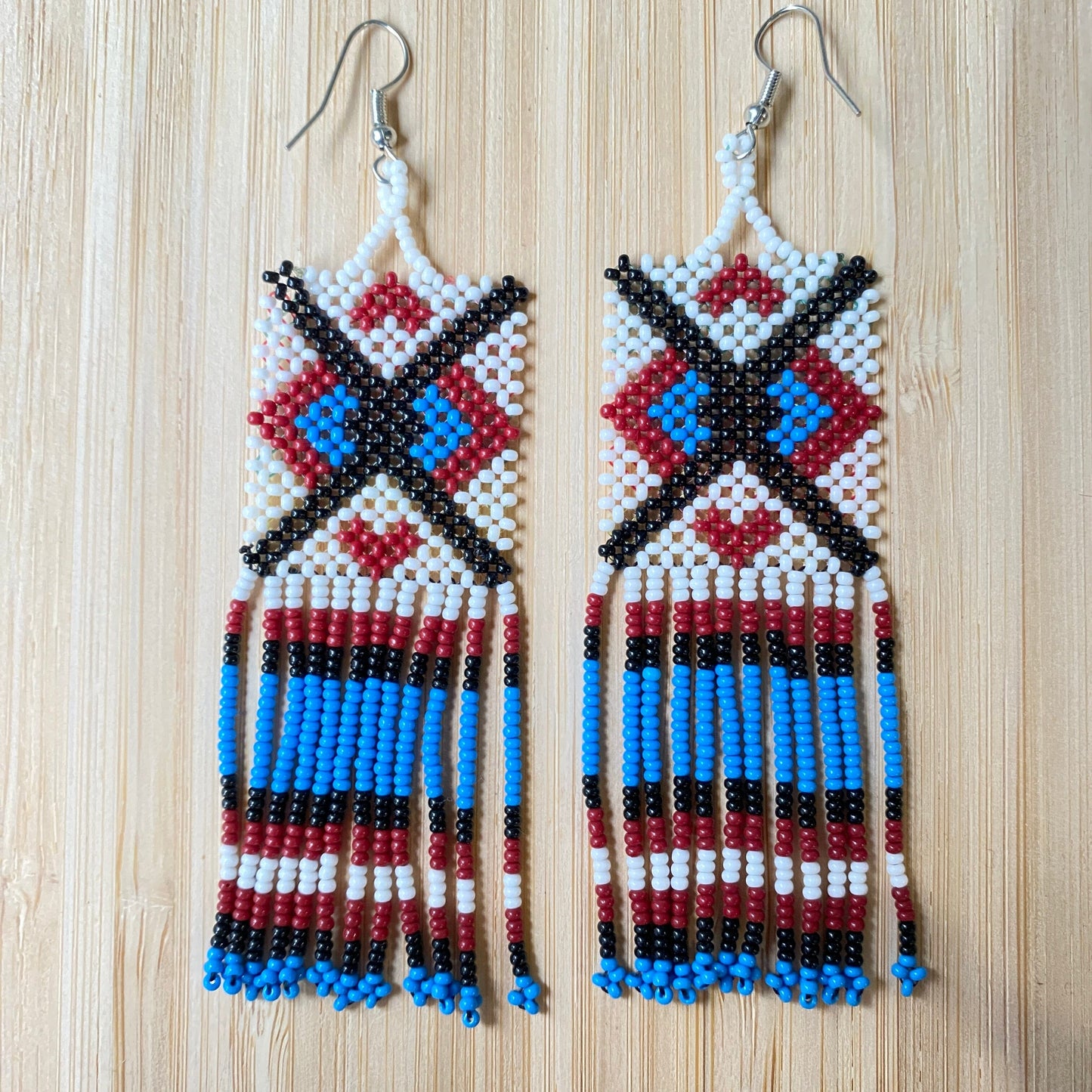 Boucles d'oreilles Miçanga - Blanc bleu croix noir - Ethnie Wai Wai Boucles d'oreilles Ethnie Wai Wai localisée dans les états de l' Amazonas, Pará et Roraima dans le Nord du Brésil. 