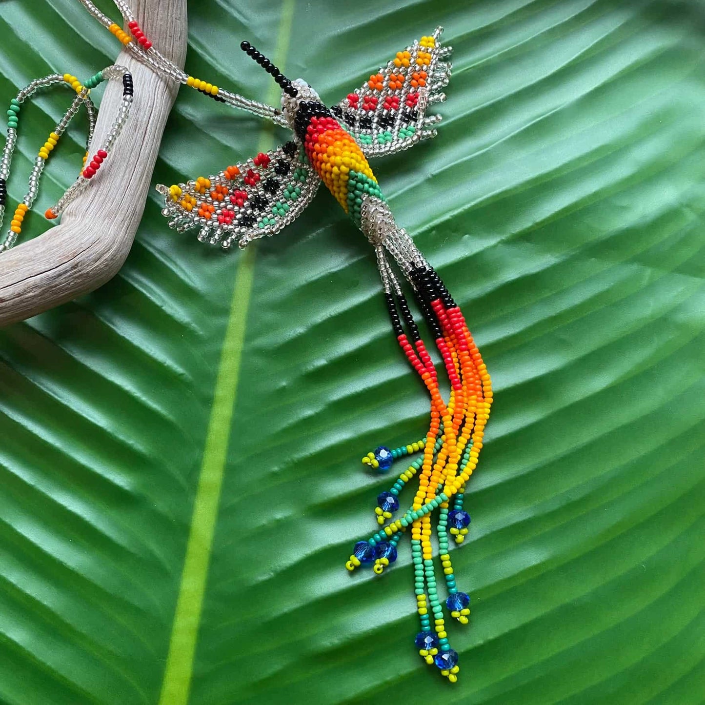 Collier en perles de verre (Miçanga) - Colibri - argenté et multicolore - Ethnie Mehinako Collier Ethnie Mehinako, localisée dans le Parc Indigène du Xingu dans l' état du Mato Grosso au Centre-Ouest du Brésil. 