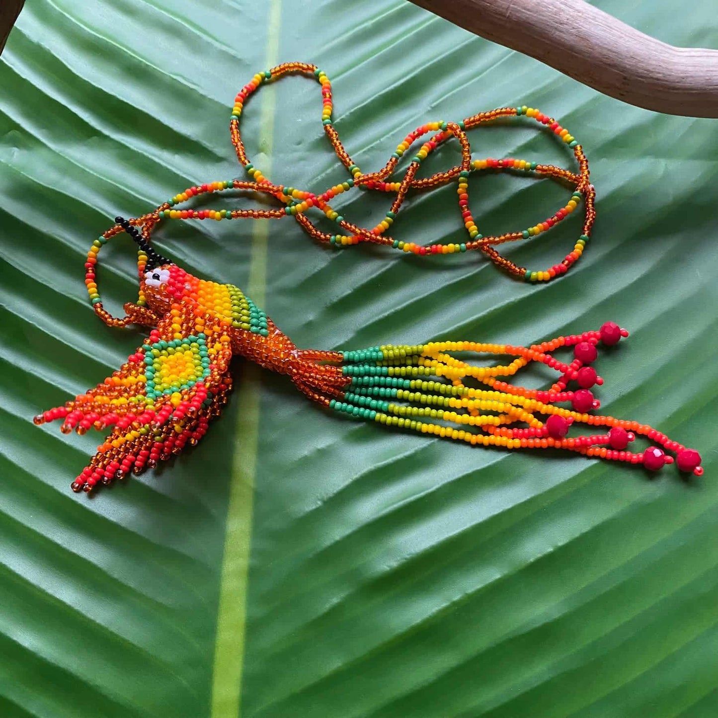 Collier en perles de verre (Miçanga) - Colibri - orange et vert - Ethnie Mehinako Collier Ethnie Mehinako, localisée dans le Parc Indigène du Xingu dans l' état du Mato Grosso au Centre-Ouest du Brésil. 