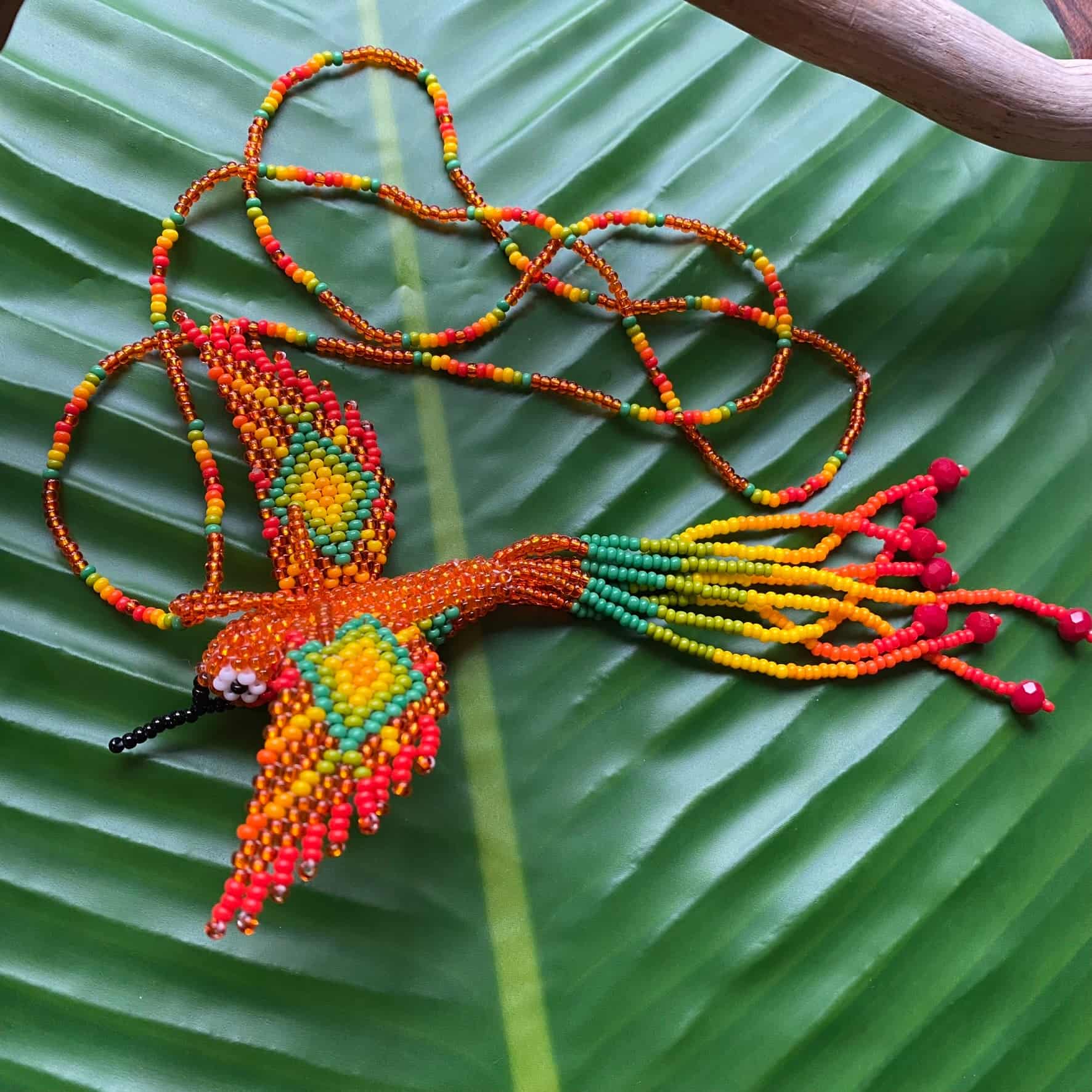 Collier en perles de verre (Miçanga) - Colibri - orange et vert - Ethnie Mehinako Collier Ethnie Mehinako, localisée dans le Parc Indigène du Xingu dans l' état du Mato Grosso au Centre-Ouest du Brésil. 